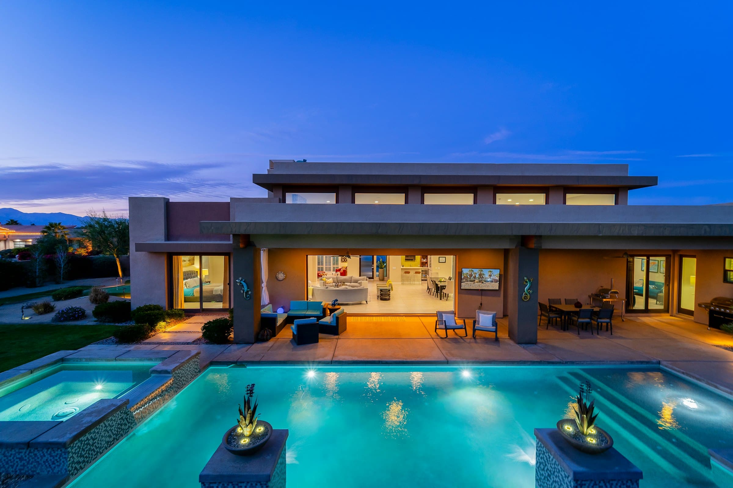 A contemporary home at twilight, interior and pool lighting glowing